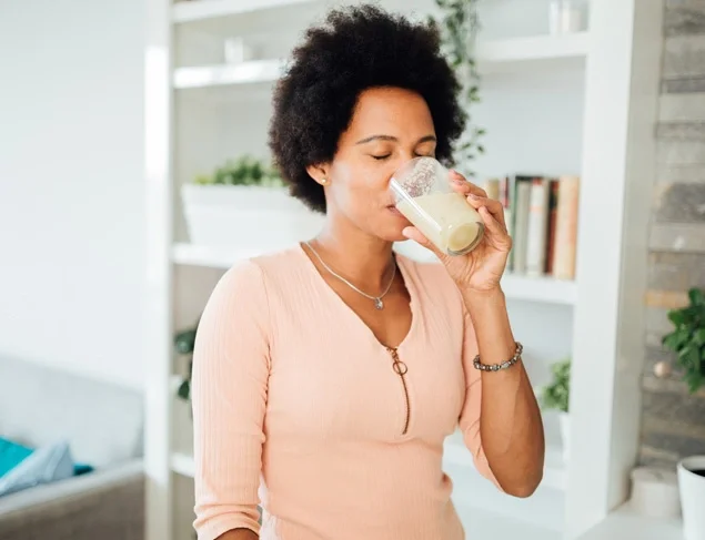 Woman in her kitchen drinking a collagen powder smoothie in the morning