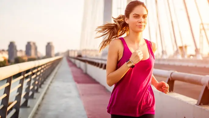 Woman having an early morning run in the city wearing a smart watch tracker