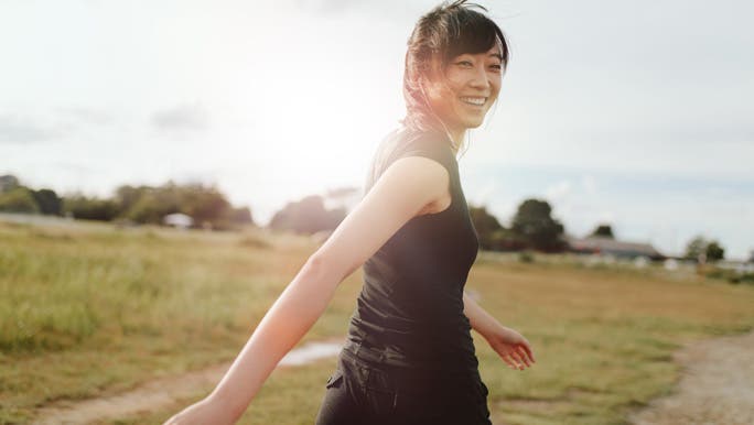 Happy woman smiling over her shoulder and walking in the park