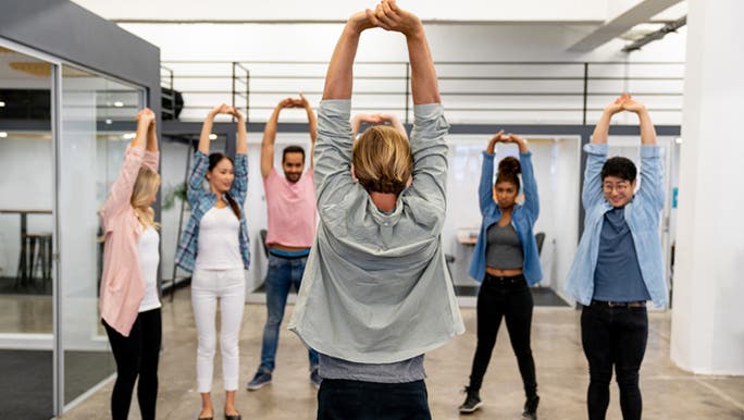 A group of office workers are practising Mindfulness Monday by doing group stretching