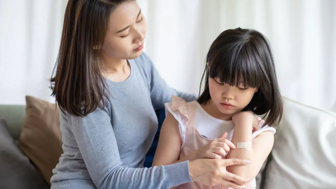 Women putting adhesive bandage on daughter