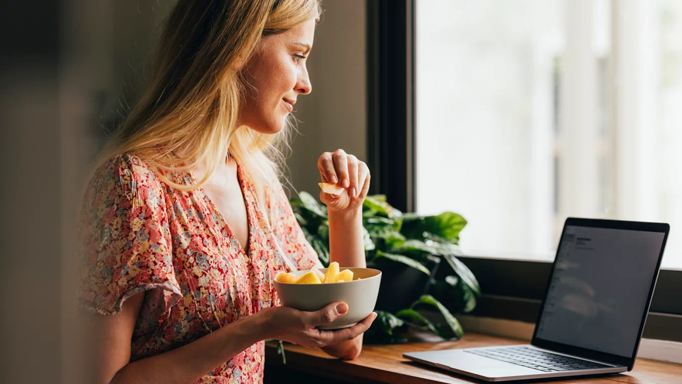 woman-stares-at-computer-eating-healthy-food.webp