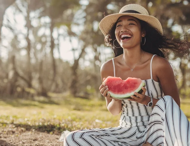 Happy woman eating watermelon outdoors