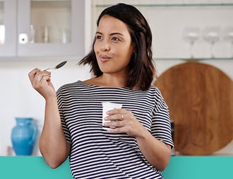 Woman in the kitchen snacking on yoghurt