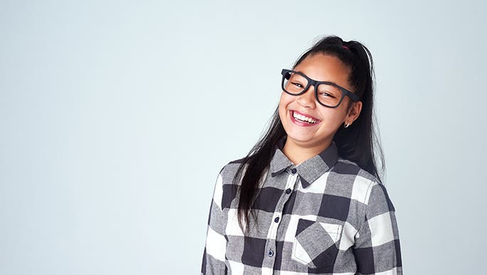 A tween with thick black glasses smiles directly into the camera. 