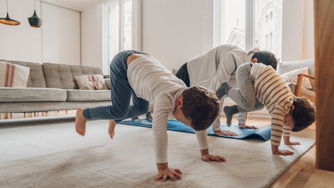 A family is doing some kid friendly exercise in their home. 