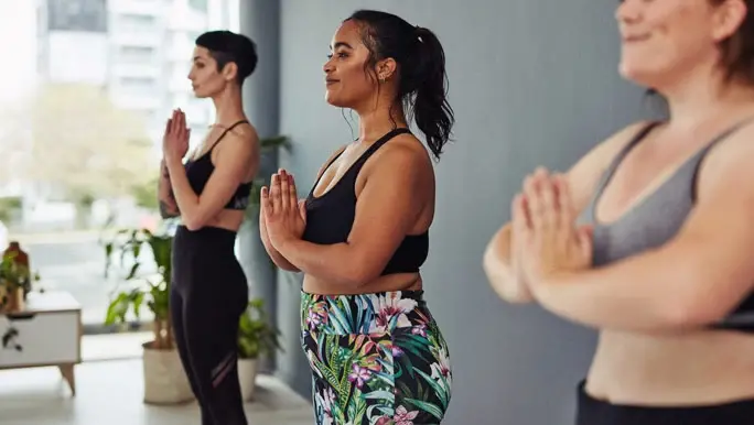 Three women in tadasana pose in a yoga class