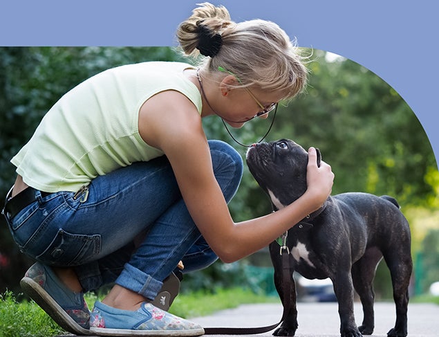 Woman crouching down to pat her dog while out walking