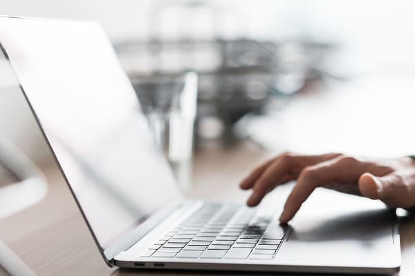 Close-up of a person's hand working on a laptop.