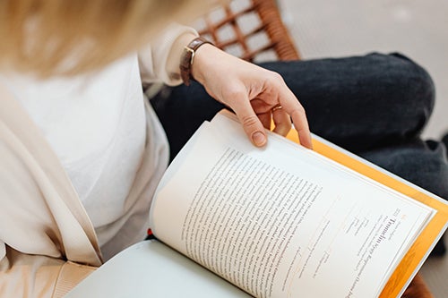 Woman studying with an open book on her lap.