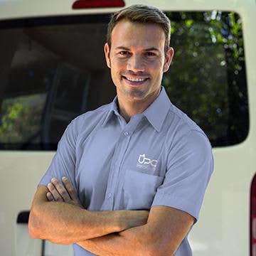 UPC technician with arms crossed in front of company van smiling