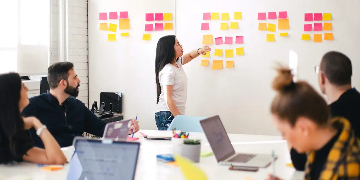 a group of co-workers planning a project with post-its on a wall