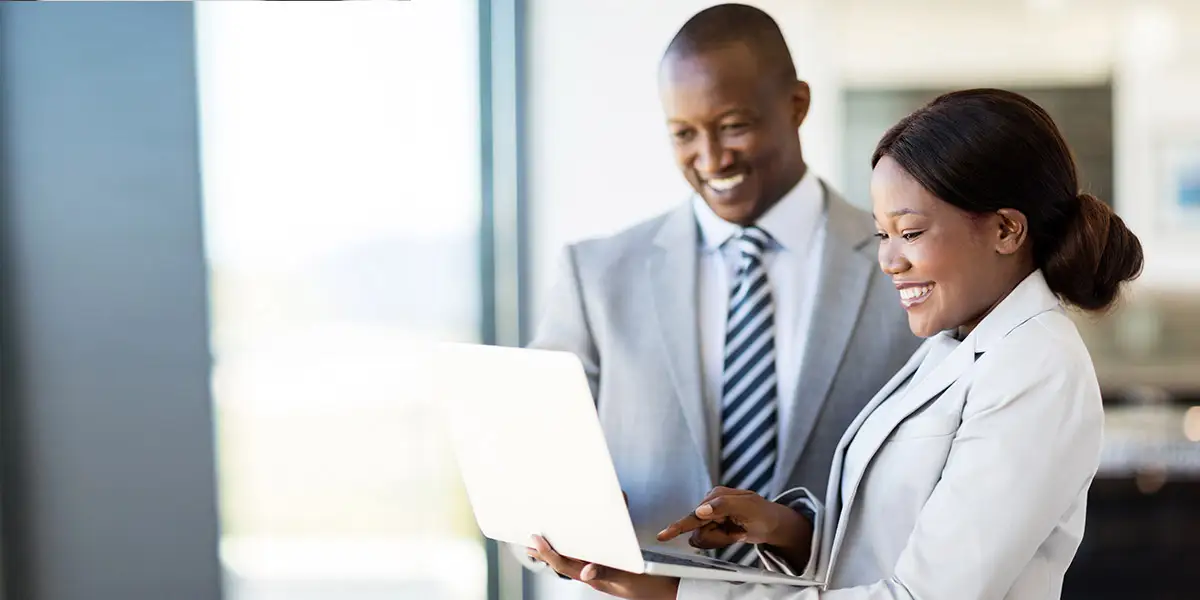 Woman in professional suit holding a laptop and showing her colleague how to design a learning journey?fm=webp&q=65