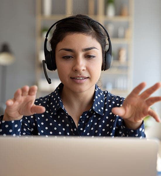 woman with headset on and hands in the air as she participates in microlearning as part of her leadership development program?auto=format&q=75