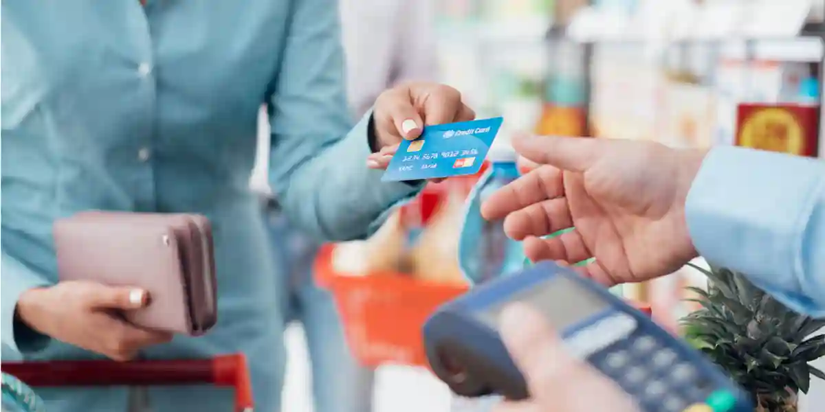 a customer giving their credit card to a cashier at a grocery store checkout 