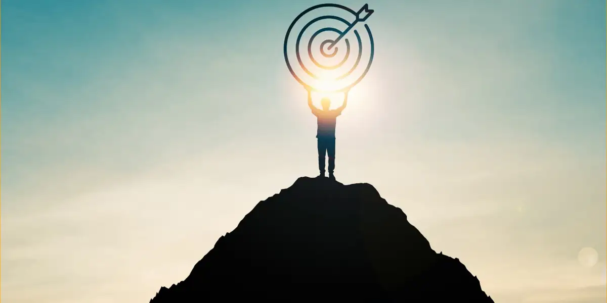 a person standing on a mountain holding a target with arrow in the bullseye