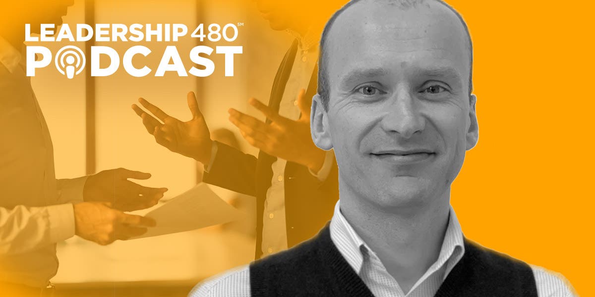 headshot of DDI leadership expert Chris Helm, the special guest on this episode of the Leadership 480 podcast, with a photo of two business professionals in a heated conversation in the background to show that this podcast is about how to resolve conflict in the workplace
