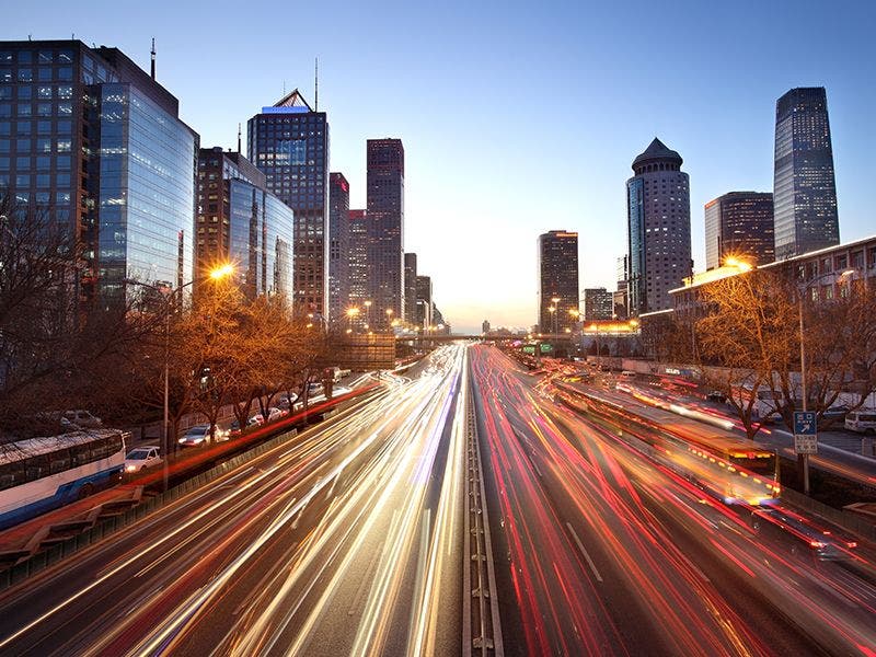 City at dusk with streaks of light showing the fast pace of traffic?auto=format&q=75