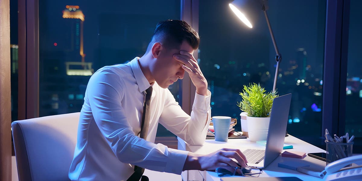 frustrated new executive sitting at his desk with head in his hand to show stress over failures