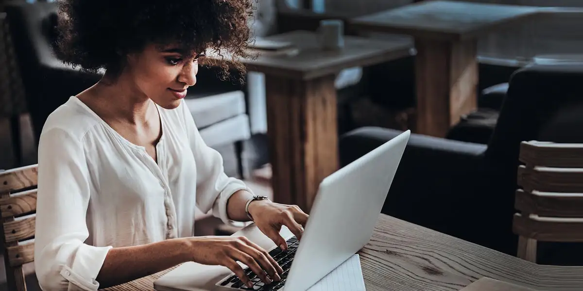 femme dans un café tapant sur un ordinateur portable