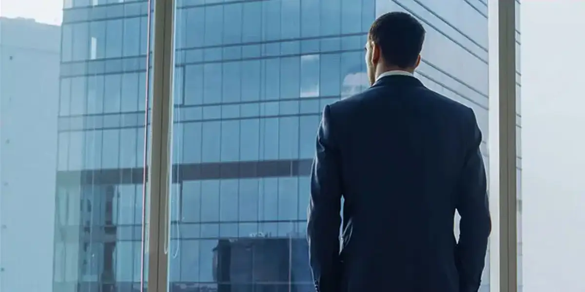 a man COO standing looking out into the distance at tall office buildings