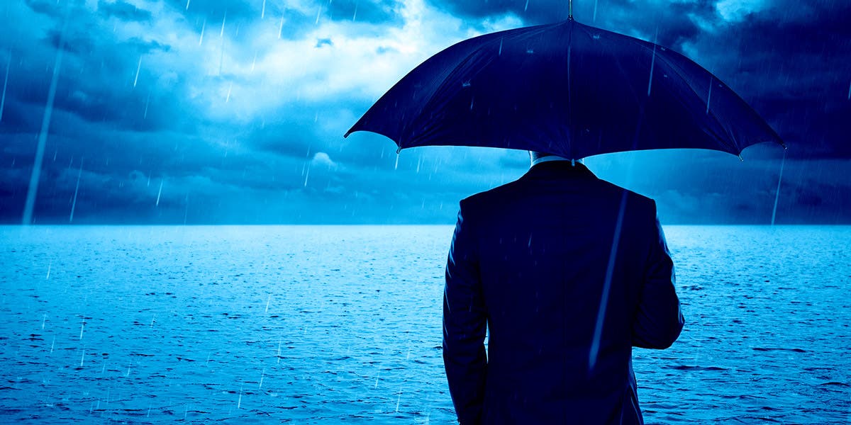 Executive standing with back to us, holding an umbrella as he looks out to a storm, which is a representation of CEO turnover