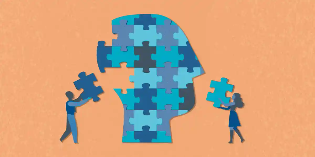 illustration of a giant head, filled with puzzle pieces, and two people are putting pieces into the head that fit within the other pieces, to show that understanding a candidate's motivational fit is an important piece of the "hiring the best person for the job" puzzle