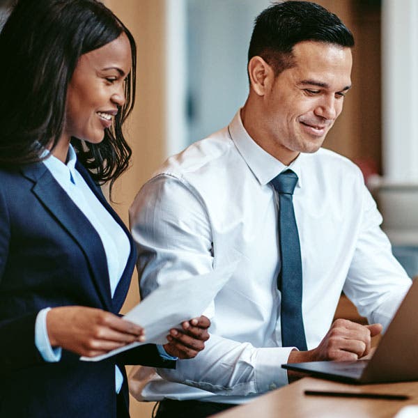 diverse business professionals looking at a computer together, all smiling ?auto=format&q=75