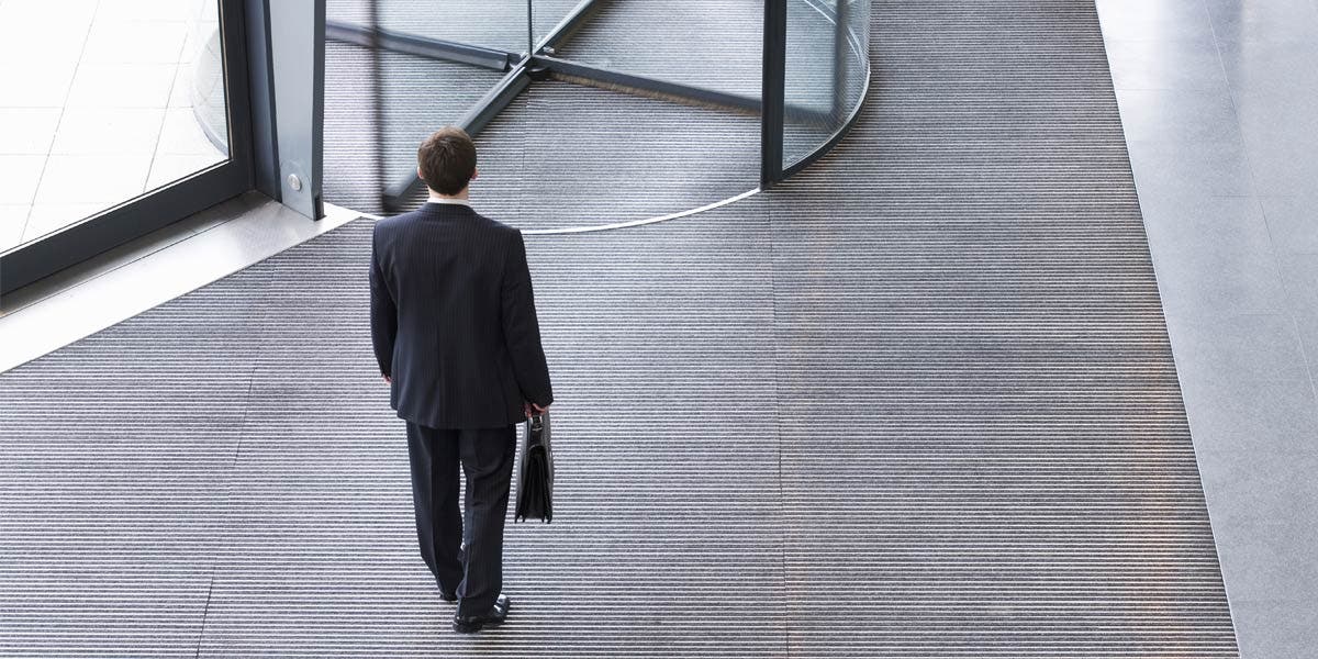 man with briefcase walking towards a revolving door