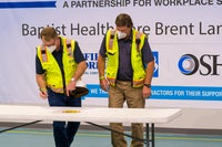 Two men in construction vests signing a paper