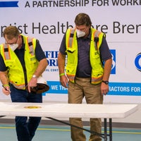 Two men in construction vests signing a paper