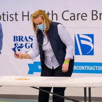 A woman handing a man a pen in front of a table
