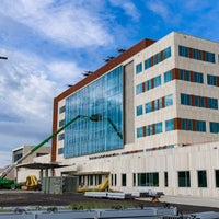 Crane working on glass panes on exterior of new campus building.