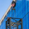 Crane holding metal piece in front of new campus building.