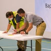 Two men looking down at a table with a pen in their hand