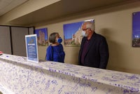 Team members pose in behind beam signing event.