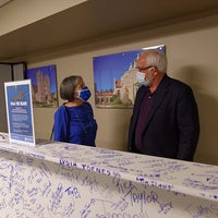 Team members pose in behind beam signing event.