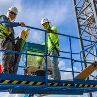 Construction workers in lift smiling at camera.