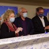 Team members pose in front of beam signing event.
