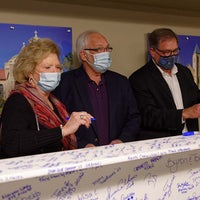 Team members pose in front of beam signing event.