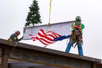 Workers holding the beam with the American flag flying 