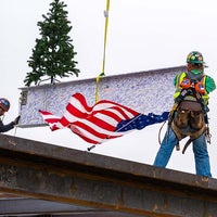 Workers holding the beam with the American flag flying 