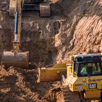 Construction vehicles digging and leveling dirt.