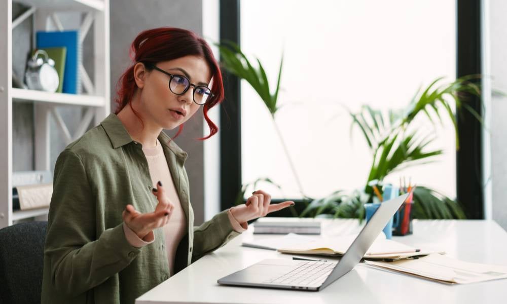 Confused frustrated employee on a video call via laptop computer while sitting at the desk indoors.jpeg