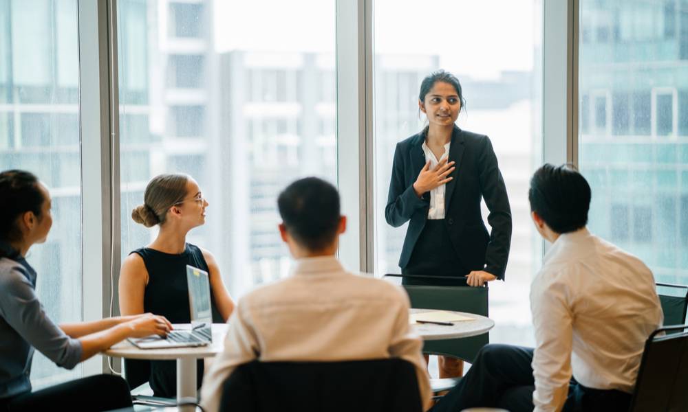 A young woman stands up in front of her team and is leading a meeting (1).jpg