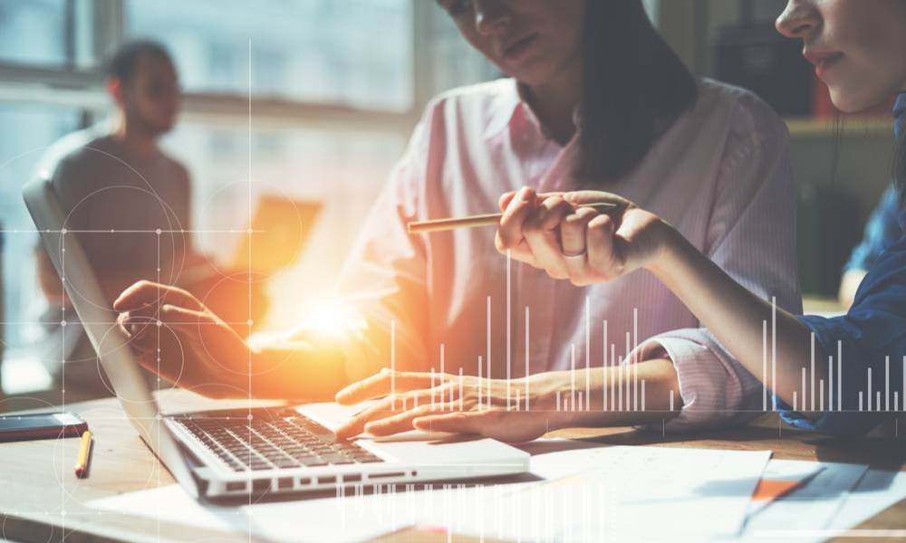 Woman pointing at laptop screen talking to another colleague clear communication is key in paradoxical leadership.jpeg