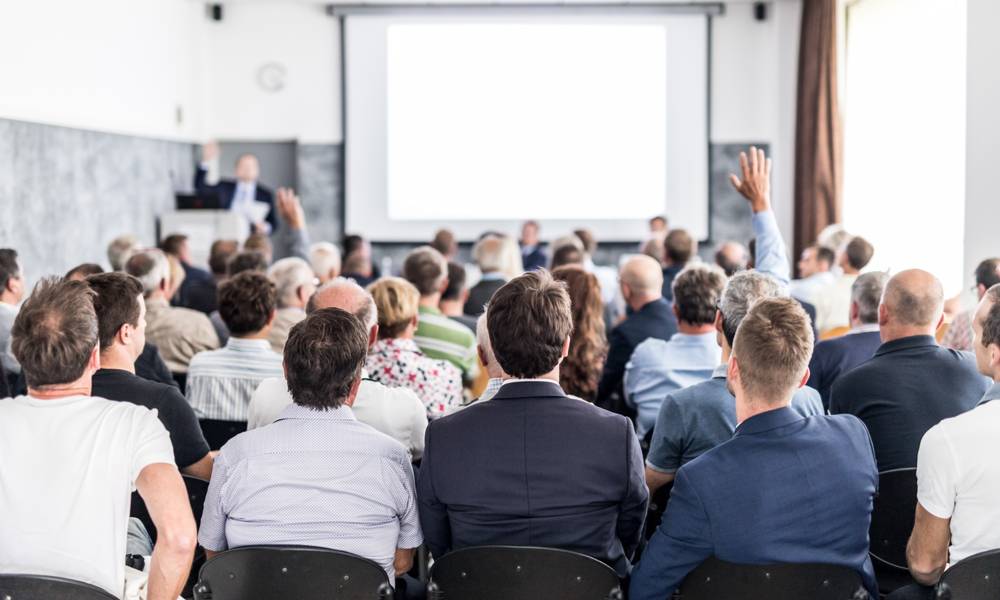 Shareholders raise hands during an annual meeting .jpeg