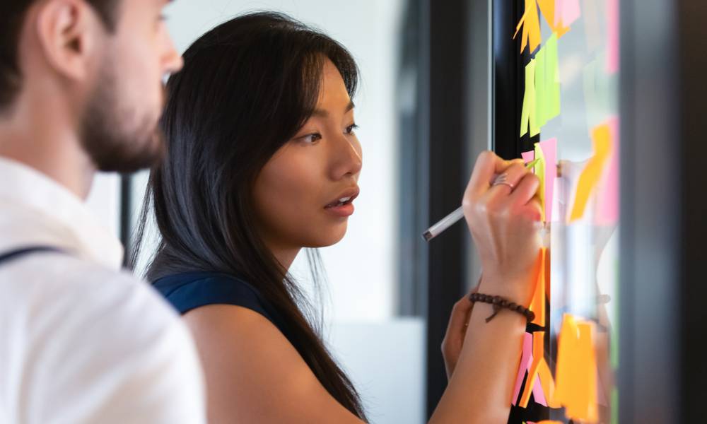 Focused business woman writing idea or task on post it sticky notes on glass wall (1).jpg