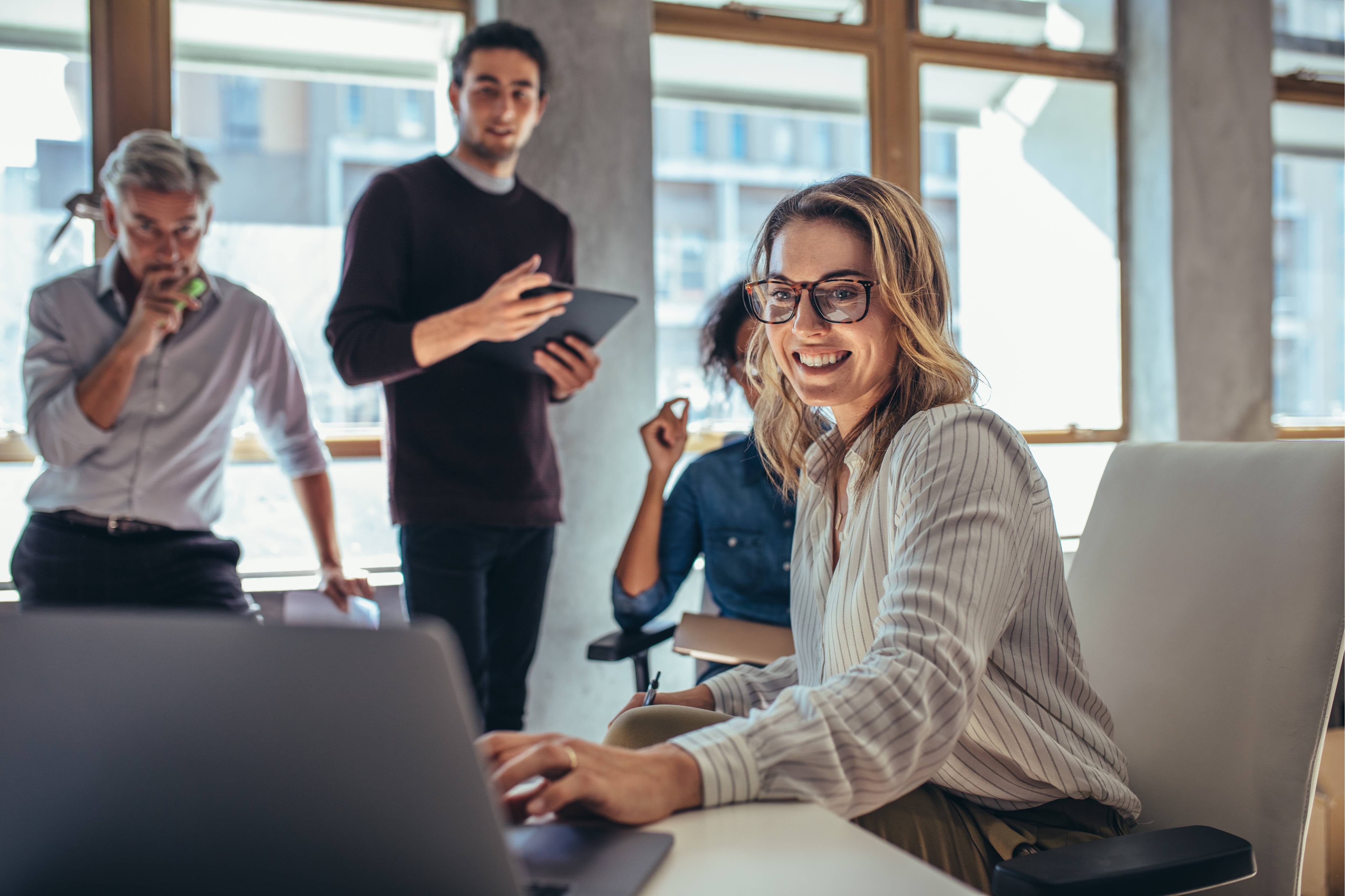 Female entrepreneur working on laptop and explaining strategy to attract followers to online web store while having meeting with colleagues in office.jpeg