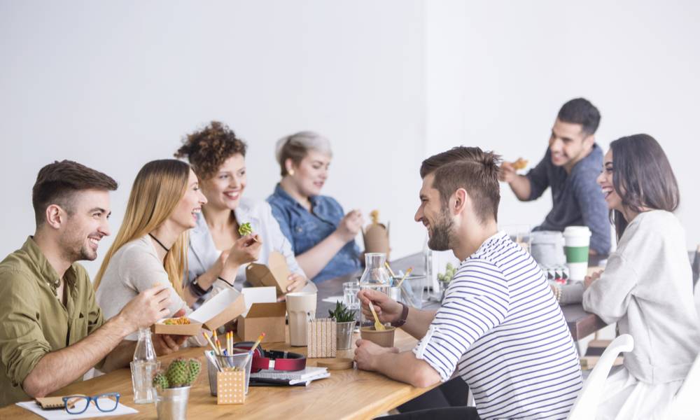 Multicultural team of coworkers eating a healthy lunch together at the office.jpeg